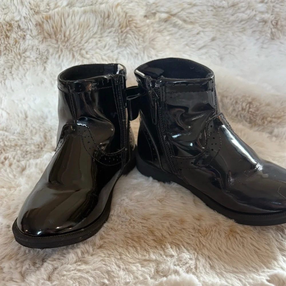 Little girls glossy black boots with bow on the back.